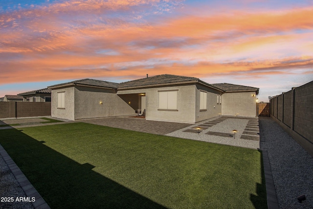 back house at dusk with a yard and a patio area