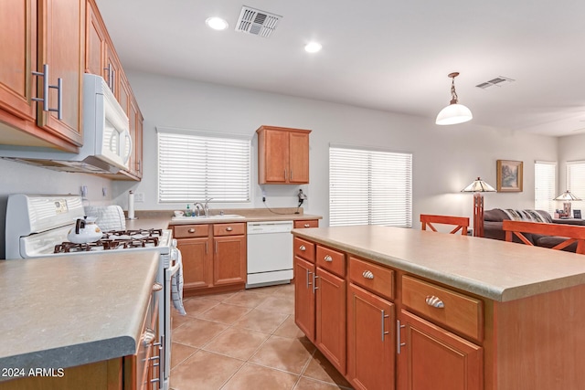 kitchen featuring a center island, light countertops, visible vents, hanging light fixtures, and white appliances