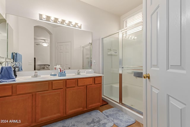 bathroom featuring ceiling fan, a sink, and a shower stall