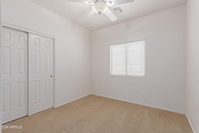 unfurnished bedroom with a closet, light colored carpet, visible vents, a ceiling fan, and baseboards