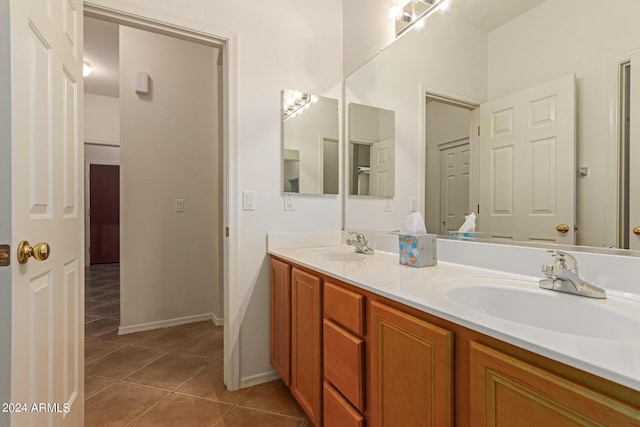 bathroom with tile patterned flooring, a sink, baseboards, and double vanity