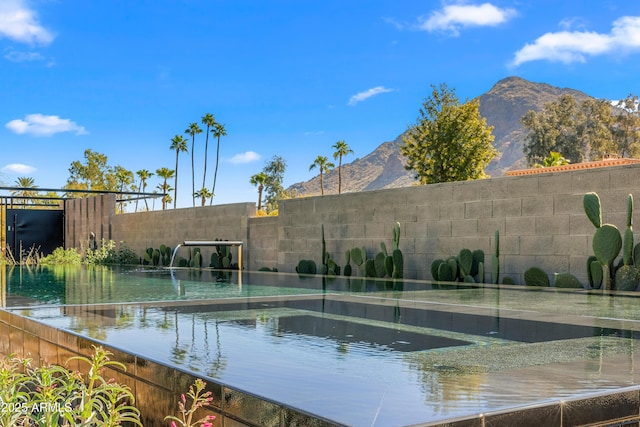 view of swimming pool featuring a mountain view and fence