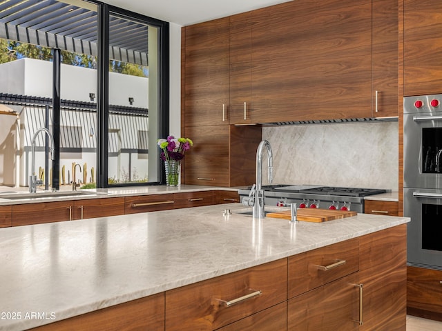 kitchen with stainless steel double oven, modern cabinets, a sink, and brown cabinets