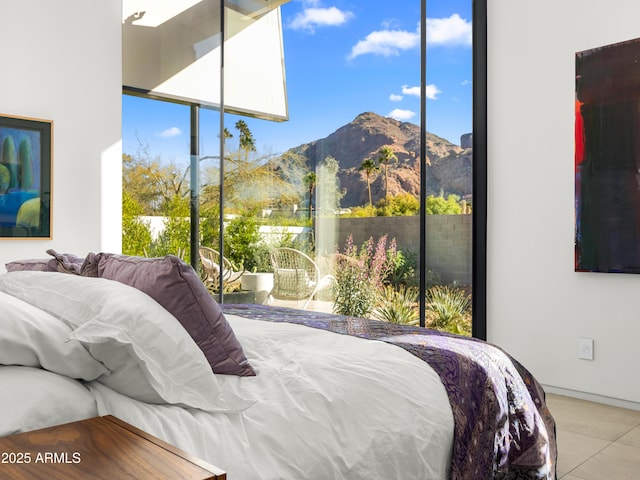 bedroom with light tile patterned floors, a wall of windows, and a mountain view