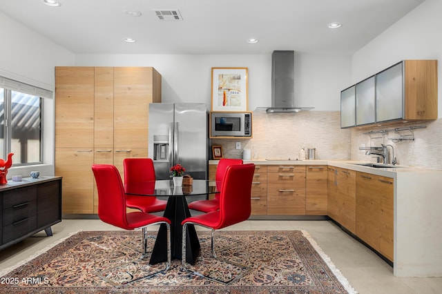 kitchen with visible vents, wall chimney exhaust hood, stainless steel appliances, light countertops, and a sink