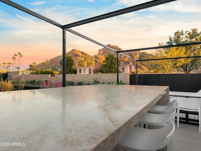 patio terrace at dusk with exterior bar, glass enclosure, and a mountain view