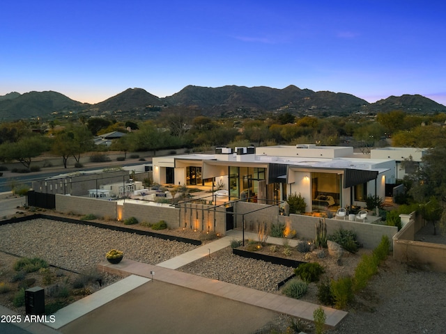 back of property at dusk featuring a fenced backyard and a mountain view