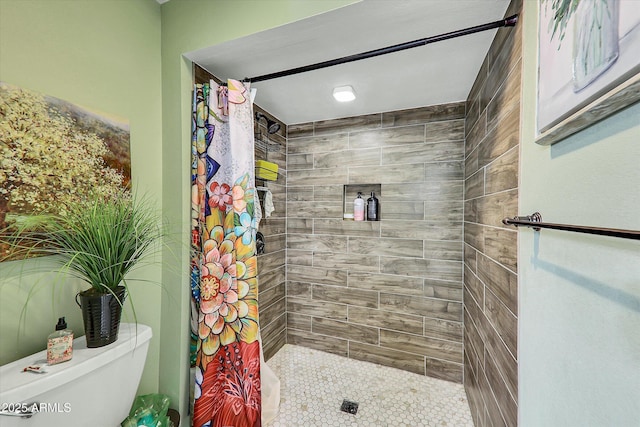 bathroom with a tile shower and toilet