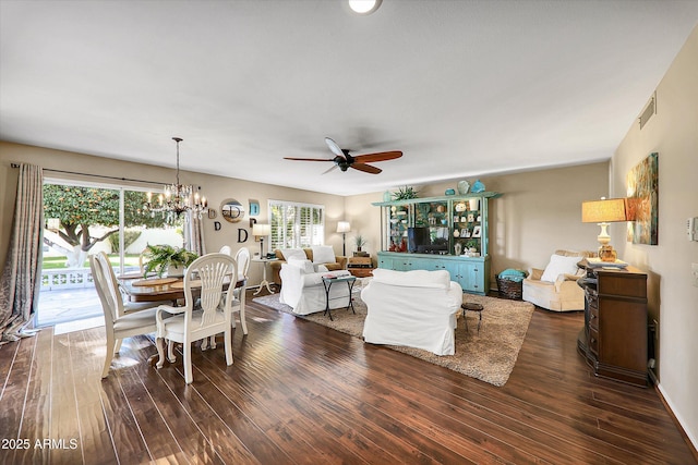 living room featuring ceiling fan with notable chandelier and dark wood-type flooring