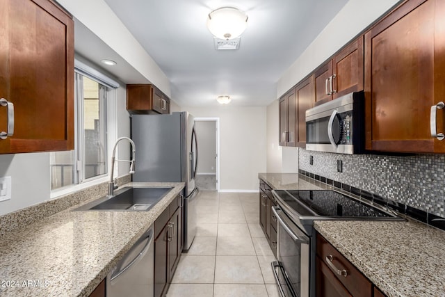 kitchen with light stone countertops, sink, decorative backsplash, light tile patterned floors, and appliances with stainless steel finishes