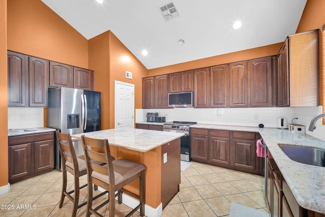 4408 W Summerside Rd, Laveen, AZ 85339 - kitchen featuring stainless steel appliances, light tile patterned floors, backsplash, a kitchen island, and high vaulted ceiling