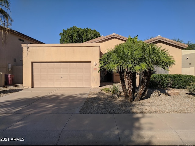 view of front facade with a garage, concrete driveway, and stucco siding