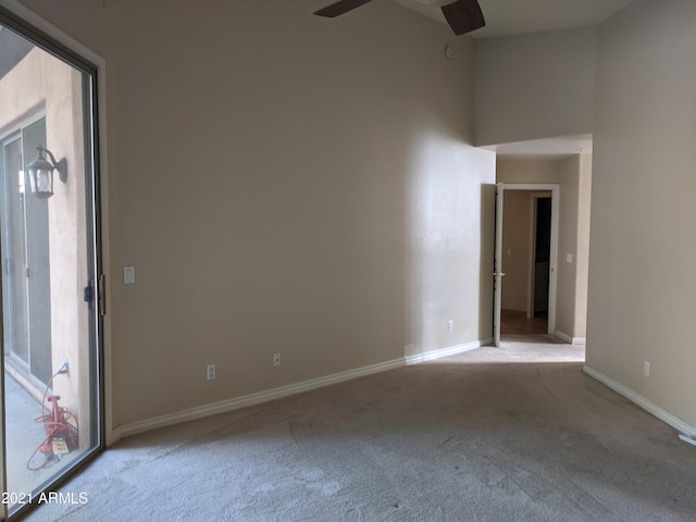 carpeted spare room with ceiling fan and a towering ceiling