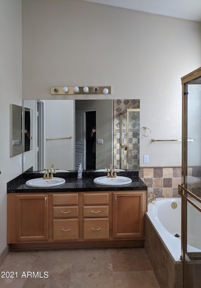 bathroom with tile patterned floors, high vaulted ceiling, plus walk in shower, and dual bowl vanity