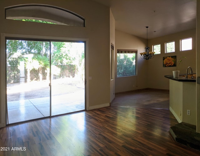 interior space with a sink, baseboards, vaulted ceiling, dark wood finished floors, and an inviting chandelier