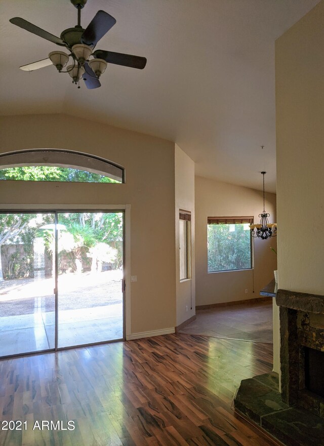 unfurnished living room with ceiling fan with notable chandelier, dark wood-type flooring, a premium fireplace, and lofted ceiling