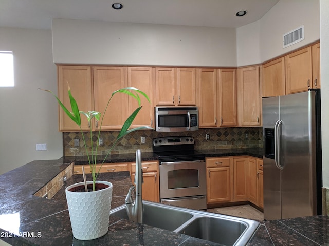 kitchen with tasteful backsplash, light brown cabinetry, light tile patterned floors, kitchen peninsula, and stainless steel appliances