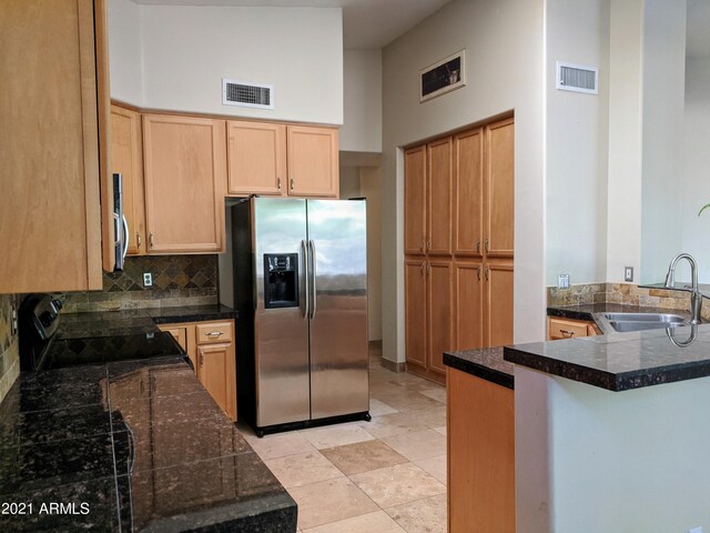 kitchen featuring backsplash, a towering ceiling, sink, kitchen peninsula, and stainless steel appliances