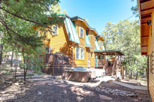 back of house with a hot tub and a deck