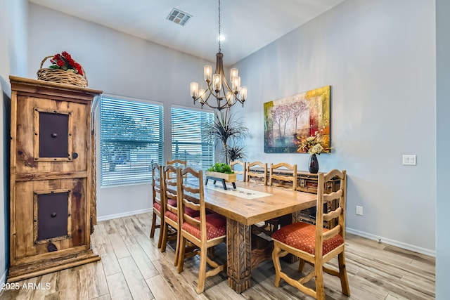 dining area with an inviting chandelier, light wood-style flooring, baseboards, and visible vents