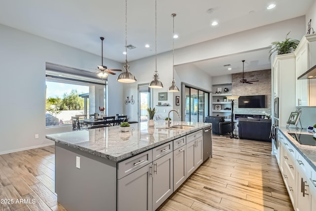 kitchen with a ceiling fan, visible vents, a sink, light wood-style floors, and open floor plan