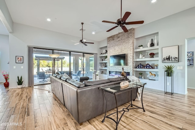 living area featuring visible vents, built in shelves, a ceiling fan, and light wood-type flooring