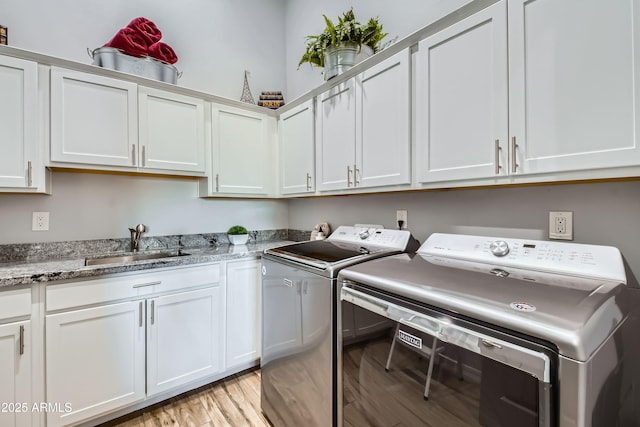 laundry area with a sink, light wood-type flooring, cabinet space, and washing machine and dryer