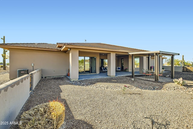 rear view of house featuring stucco siding, cooling unit, a patio, and fence