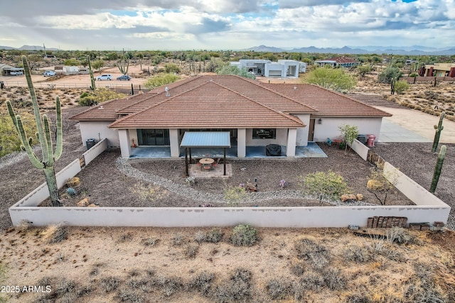 view of front of property featuring a tiled roof, stucco siding, and a patio area