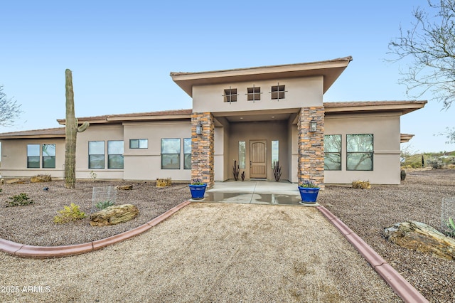 rear view of house featuring stucco siding