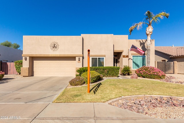 pueblo-style house featuring a garage and a front yard