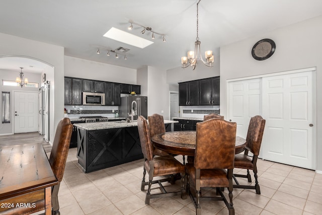 dining space featuring a notable chandelier, light tile patterned floors, and a skylight