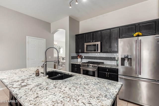 kitchen featuring light stone countertops, sink, an island with sink, and stainless steel appliances