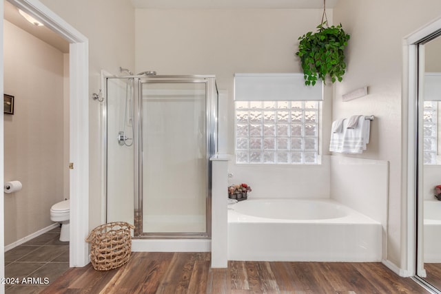 bathroom with hardwood / wood-style floors, toilet, and plus walk in shower