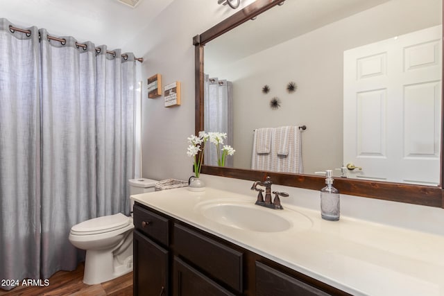 full bathroom featuring hardwood / wood-style flooring, vanity, shower / bath combination with curtain, and toilet