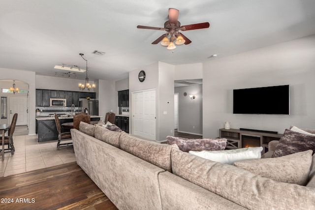 living room featuring hardwood / wood-style floors, ceiling fan with notable chandelier, and sink