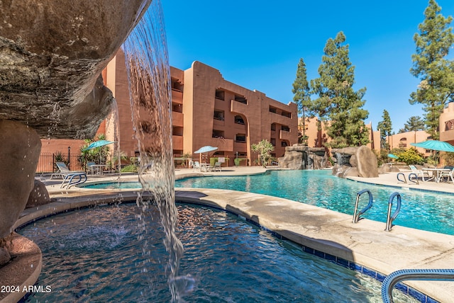 view of pool featuring a hot tub, a patio area, and pool water feature