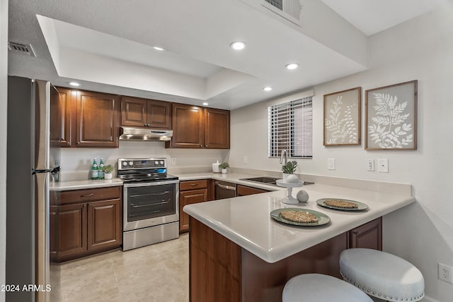 kitchen with appliances with stainless steel finishes, light tile patterned floors, sink, a kitchen breakfast bar, and kitchen peninsula