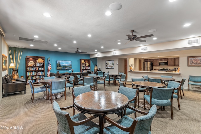 carpeted dining space with a textured ceiling and ceiling fan