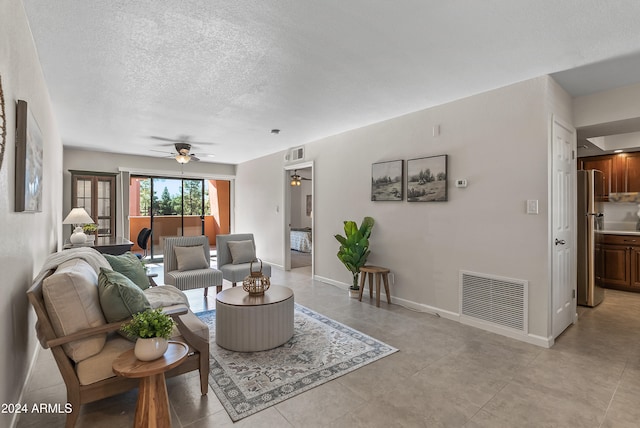 living room with ceiling fan and a textured ceiling