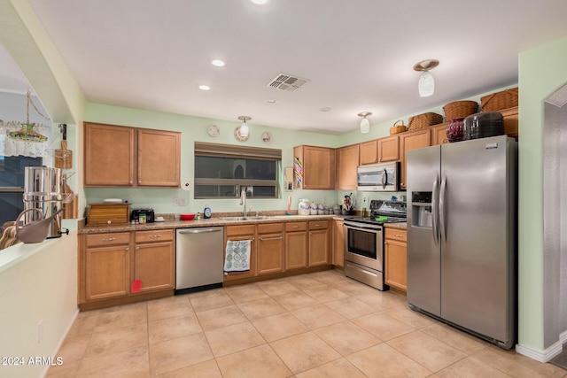 kitchen with light stone countertops, sink, light tile patterned floors, and stainless steel appliances