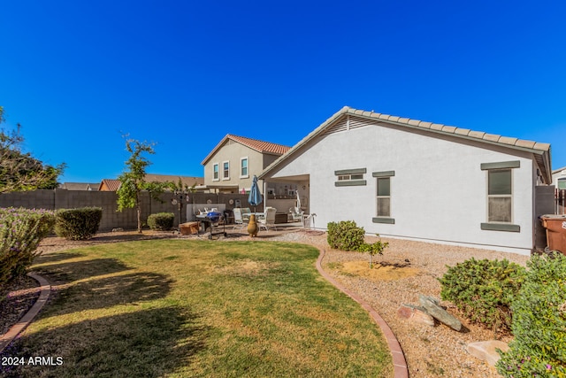 rear view of property featuring a lawn and a patio