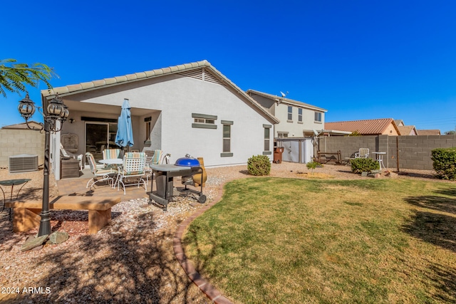 back of property featuring a lawn, a patio area, and a storage shed