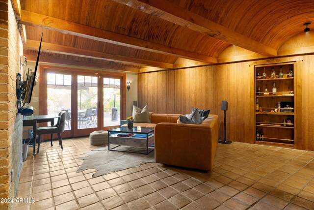 living room with vaulted ceiling with beams, wood walls, and wooden ceiling