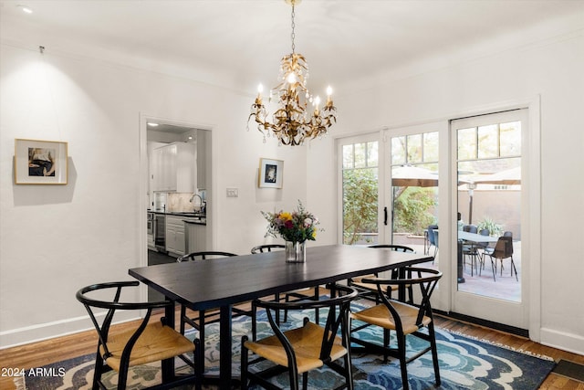 dining area featuring dark hardwood / wood-style floors, french doors, sink, and an inviting chandelier