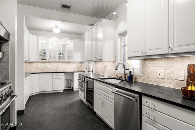 kitchen featuring decorative backsplash, stainless steel appliances, crown molding, sink, and white cabinetry