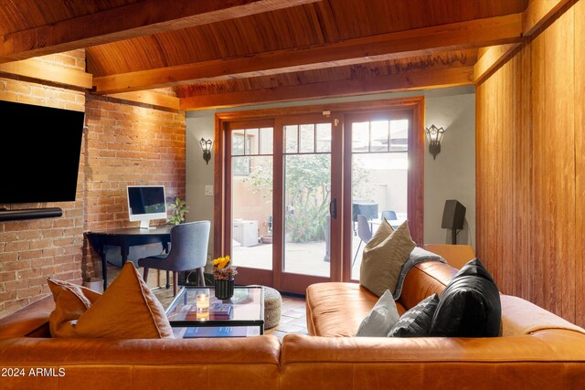 living room with beamed ceiling, wood ceiling, and brick wall