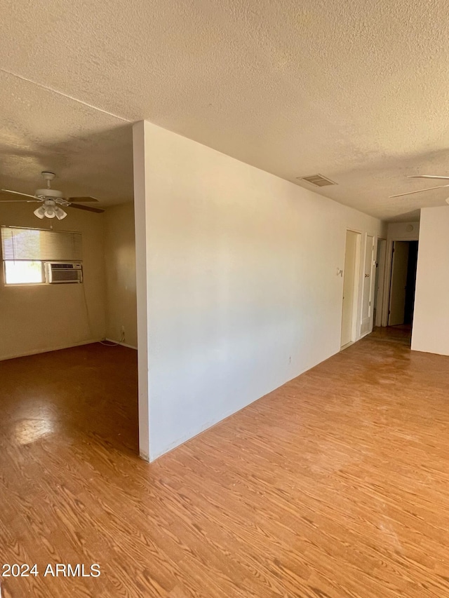 1020 W Schwartz Rd, Ajo, AZ 85321 - spare room featuring visible vents, light wood-type flooring, a textured ceiling, a wall mounted AC, and a ceiling fan