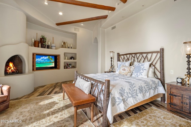 bedroom with lofted ceiling with beams and light wood-type flooring