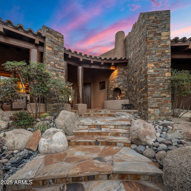 patio terrace at dusk with an outdoor stone fireplace